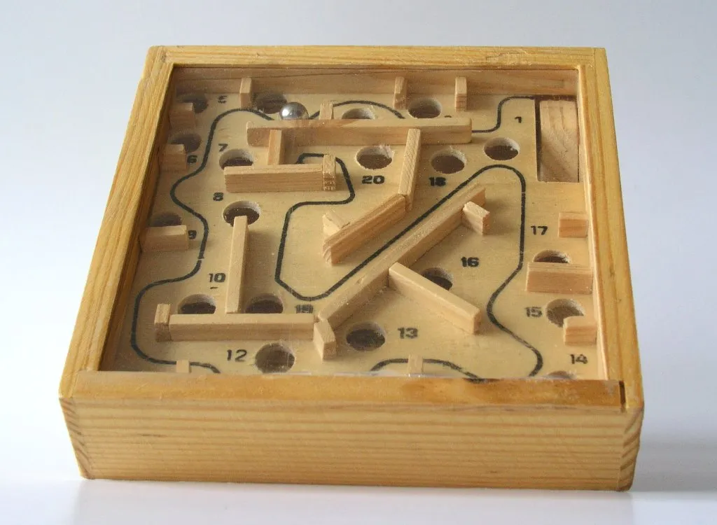 A classic wooden ball-in-a-maze board: wooden frame, maze walls, numbered holes, and a steel ball